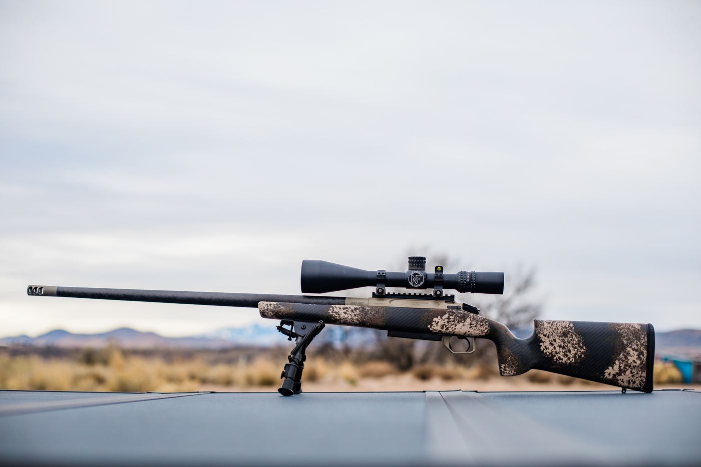 Custom rifle on the truck hood, Western desert behind